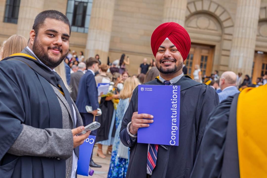 Two graduates celebrating outside Caird Hall